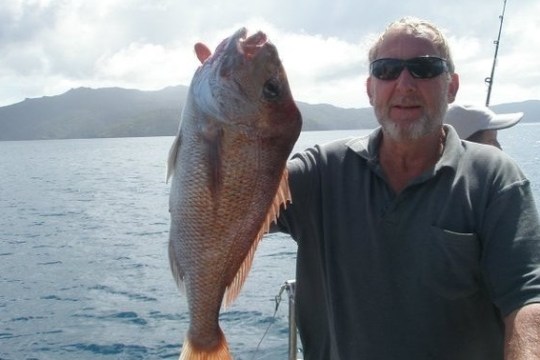a man holding a fish on a boat in a body of water