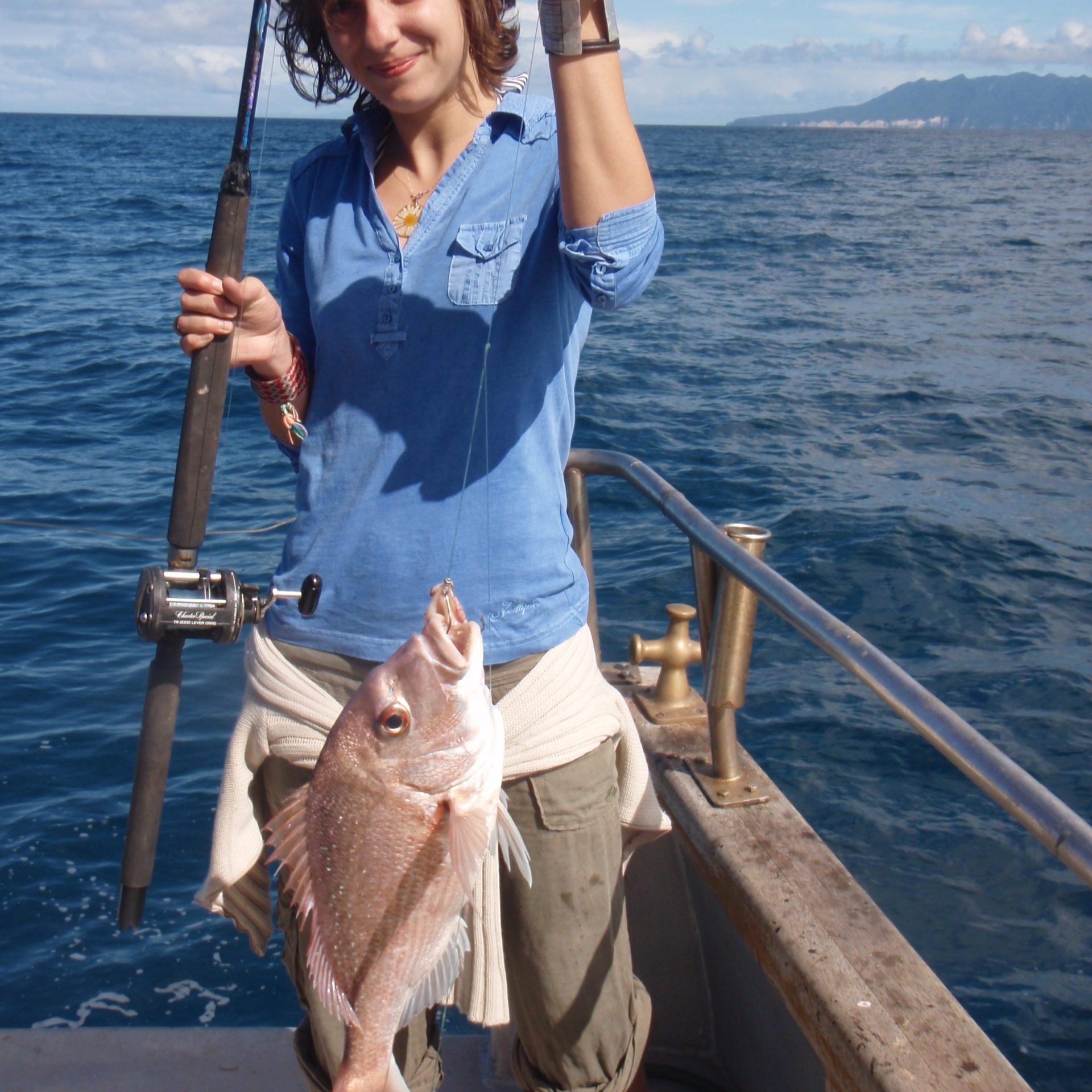 a person holding a fish on a boat in a body of water